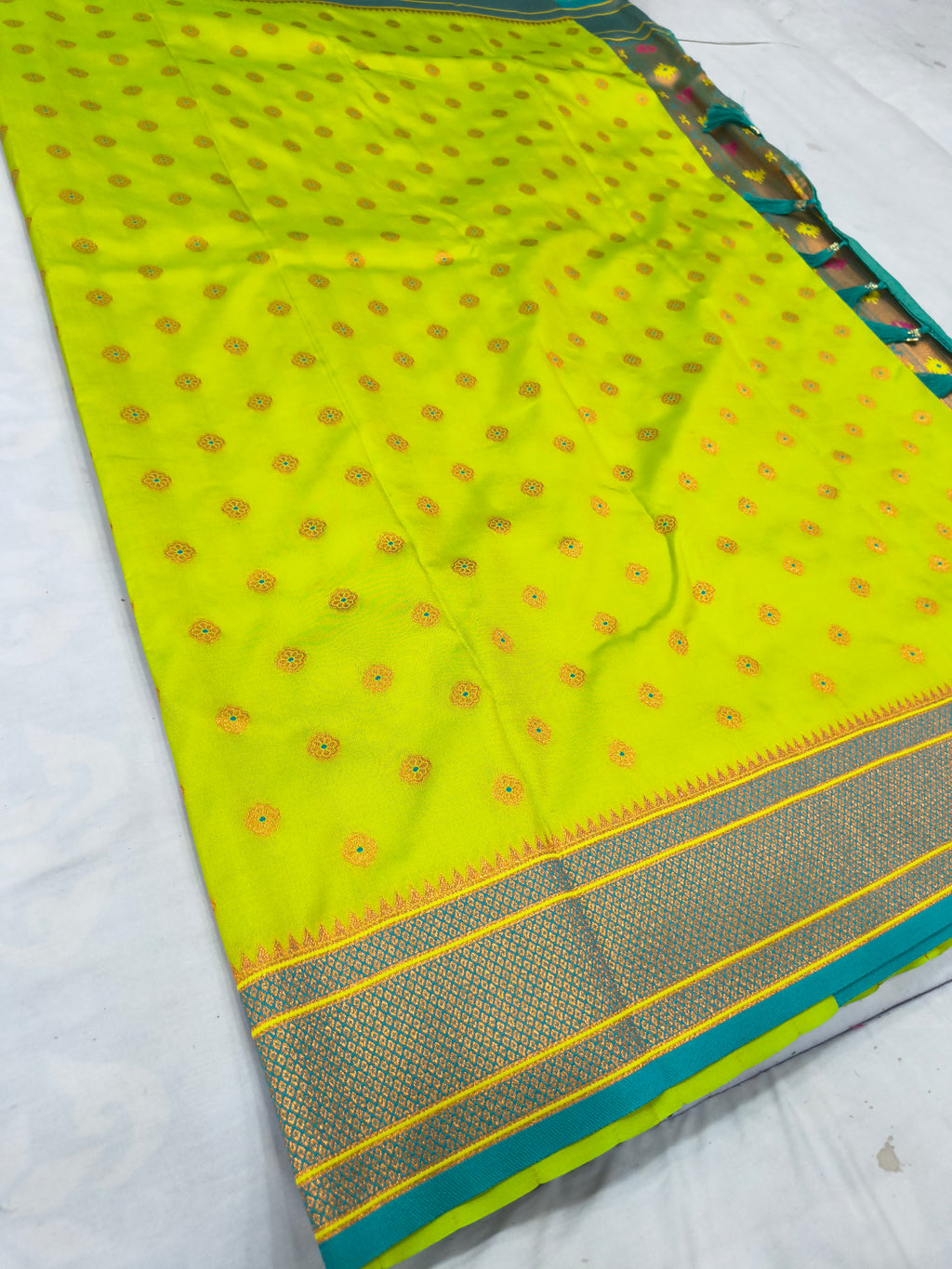 Neon yellow saree with scattered red-gold motifs and navy-blue woven border, teal edge