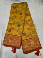 Mustard yellow silk saree with floral vine pattern and red border, unstitched blouse