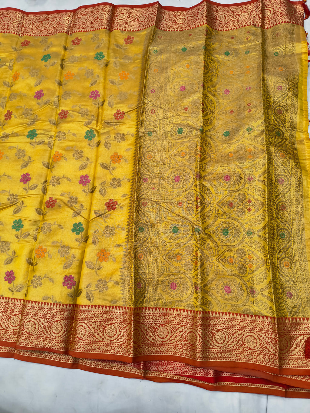 Mustard yellow silk saree with floral jaal motifs, wide red-gold border and tassels