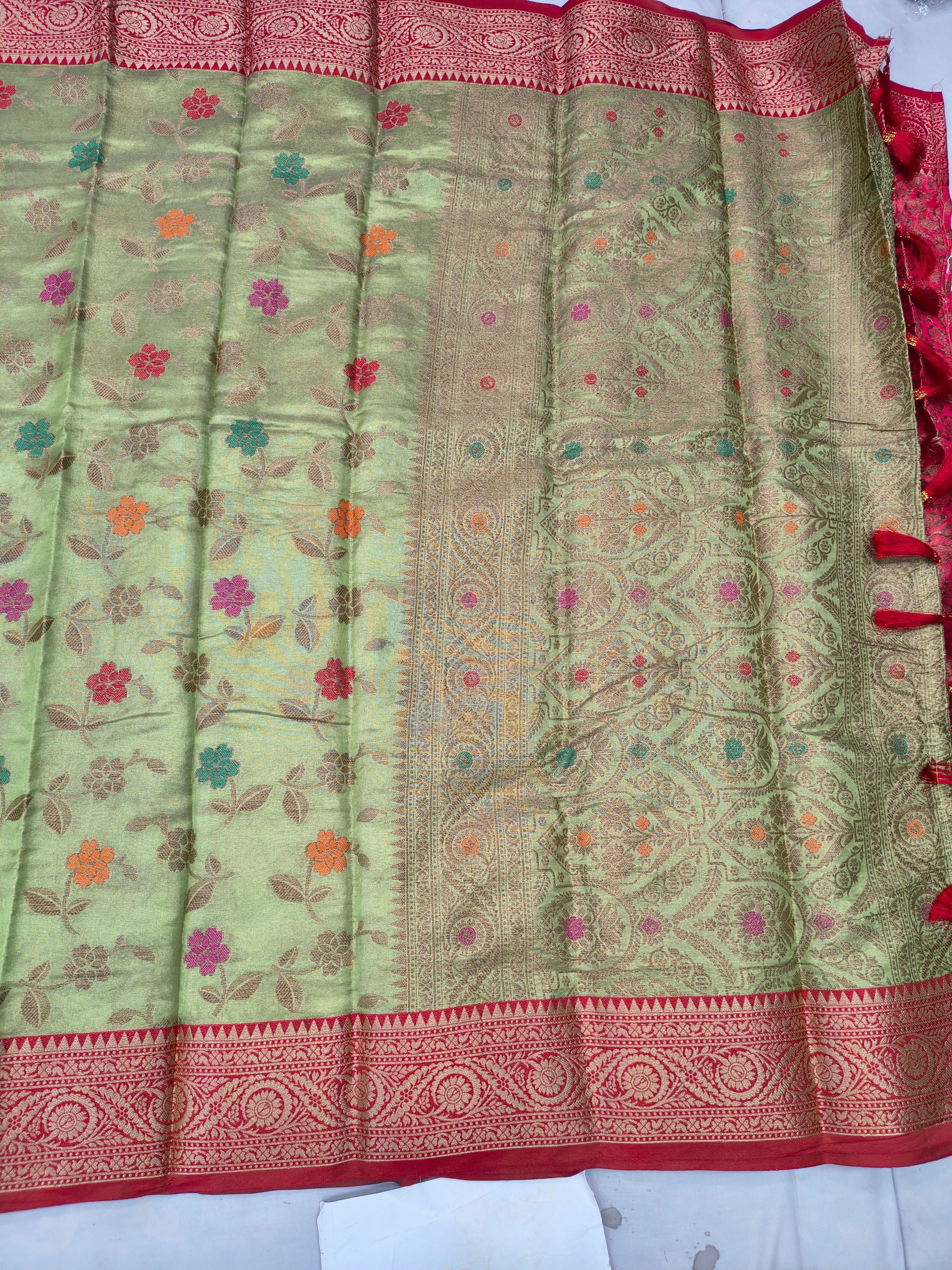 Light green silk saree with colorful floral pattern and red zari border strip