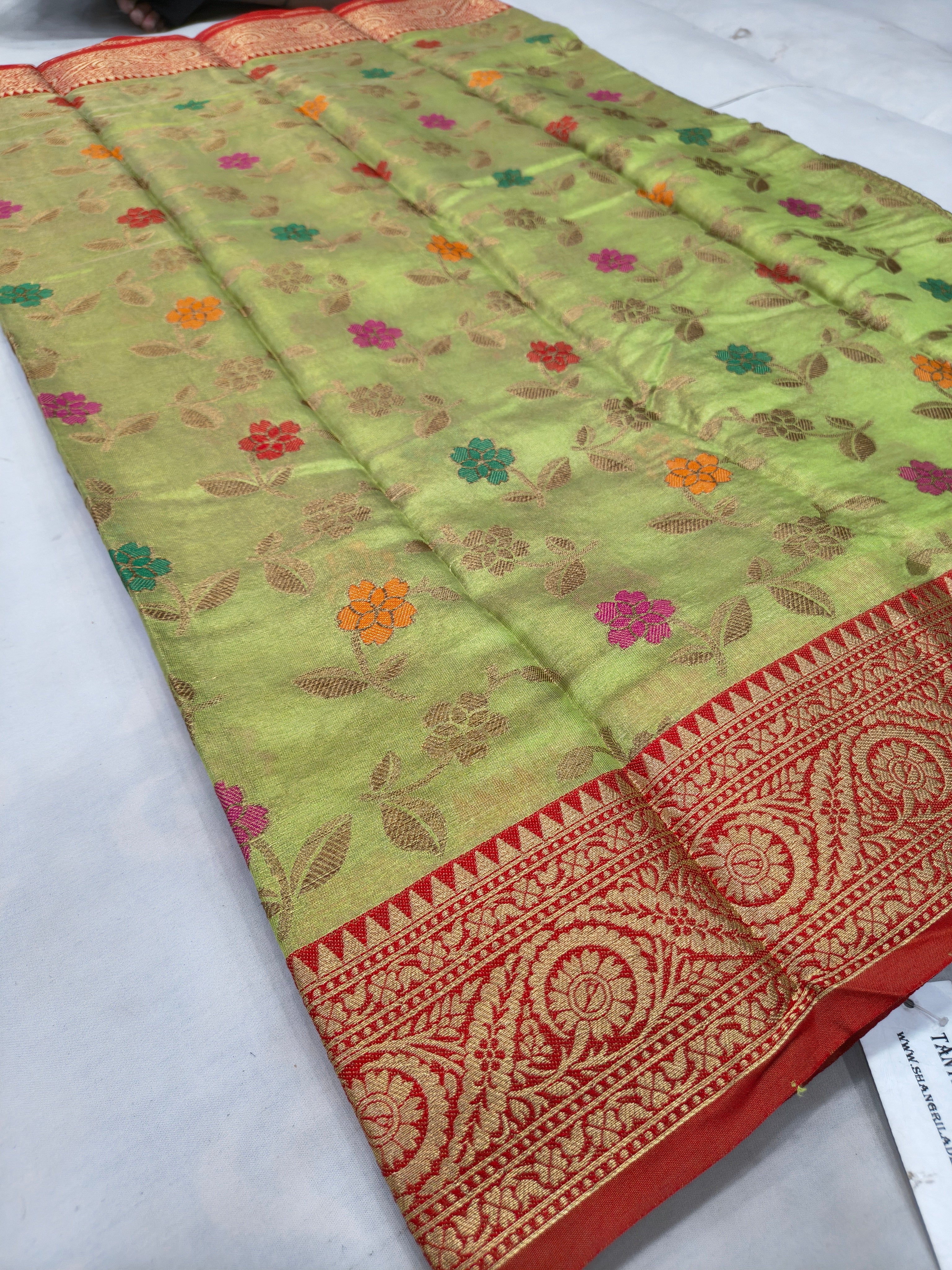 Light green silk saree with multi-color floral motifs and red patterned border