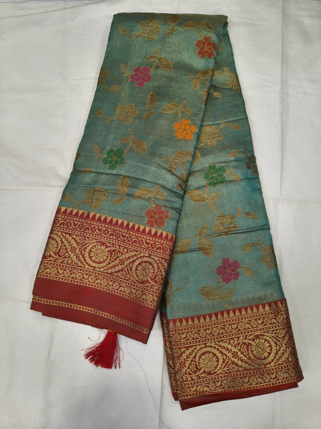 Teal sky-blue silk saree with red-gold Kanchipuram-style border and floral motifs