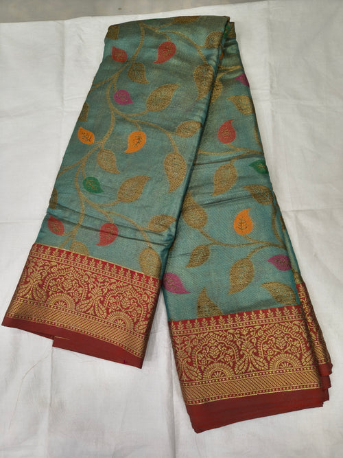 Turquoise silk saree with multicolor leaf print and red-gold woven border, folded