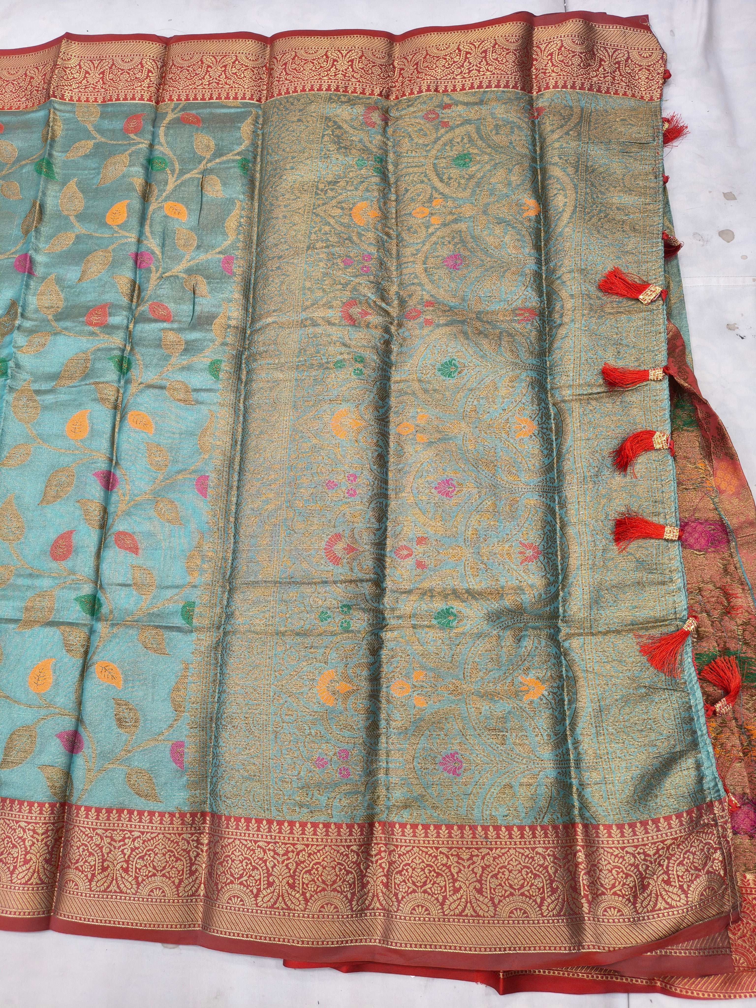 Turquoise saree with gold and red motifs, wide patterned border and pleated panels