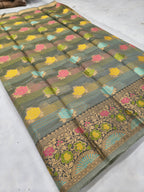 Dark grey silk saree laid flat with colorful flowers, striped bands, and gold border