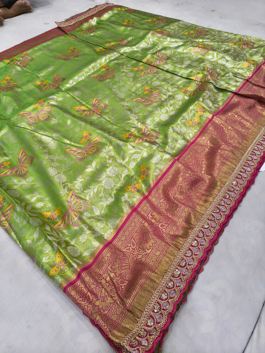Light green silk saree with pink-gold border and allover patterned motifs, laid flat