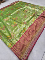 Light green silk saree with pink-gold border and allover patterned motifs, laid flat