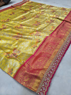 Yellow Banarasi silk saree with floral motifs and wide pink-gold border