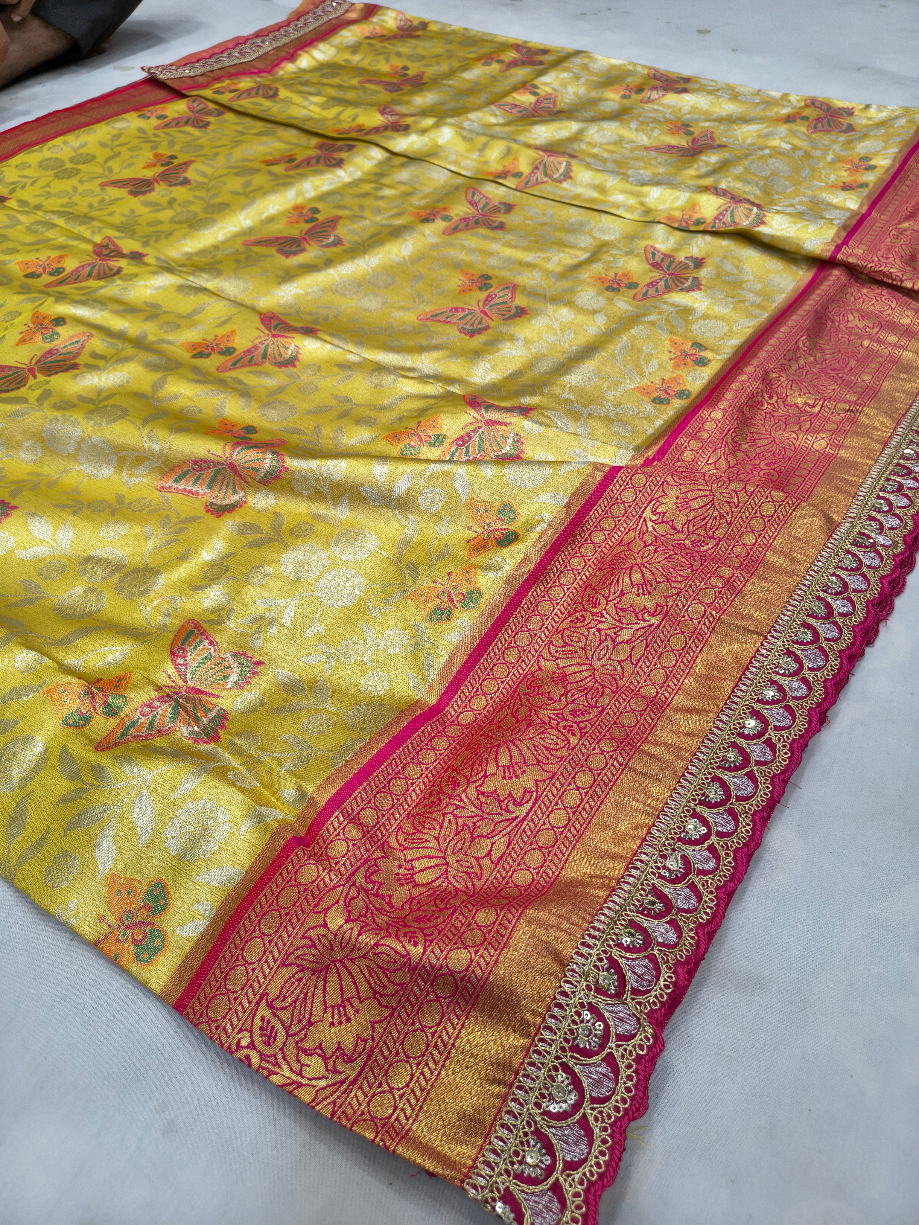Yellow Banarasi silk saree with floral motifs and wide pink-gold border