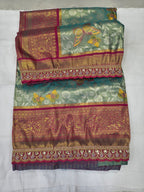 Folded teal-green Banarasi silk saree with pink bands and ornate zari-style border