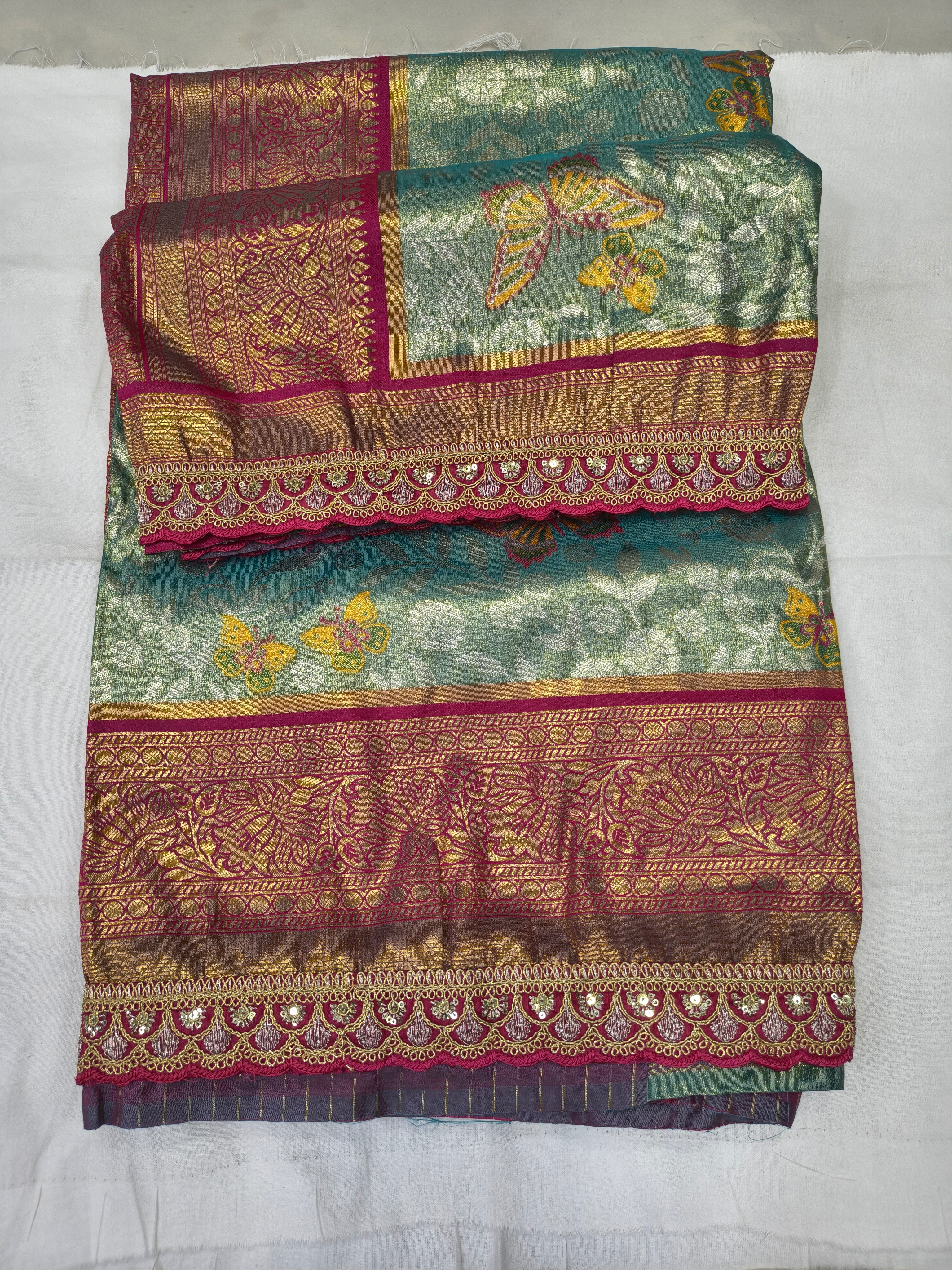 Folded teal-green Banarasi silk saree with pink bands and ornate zari-style border