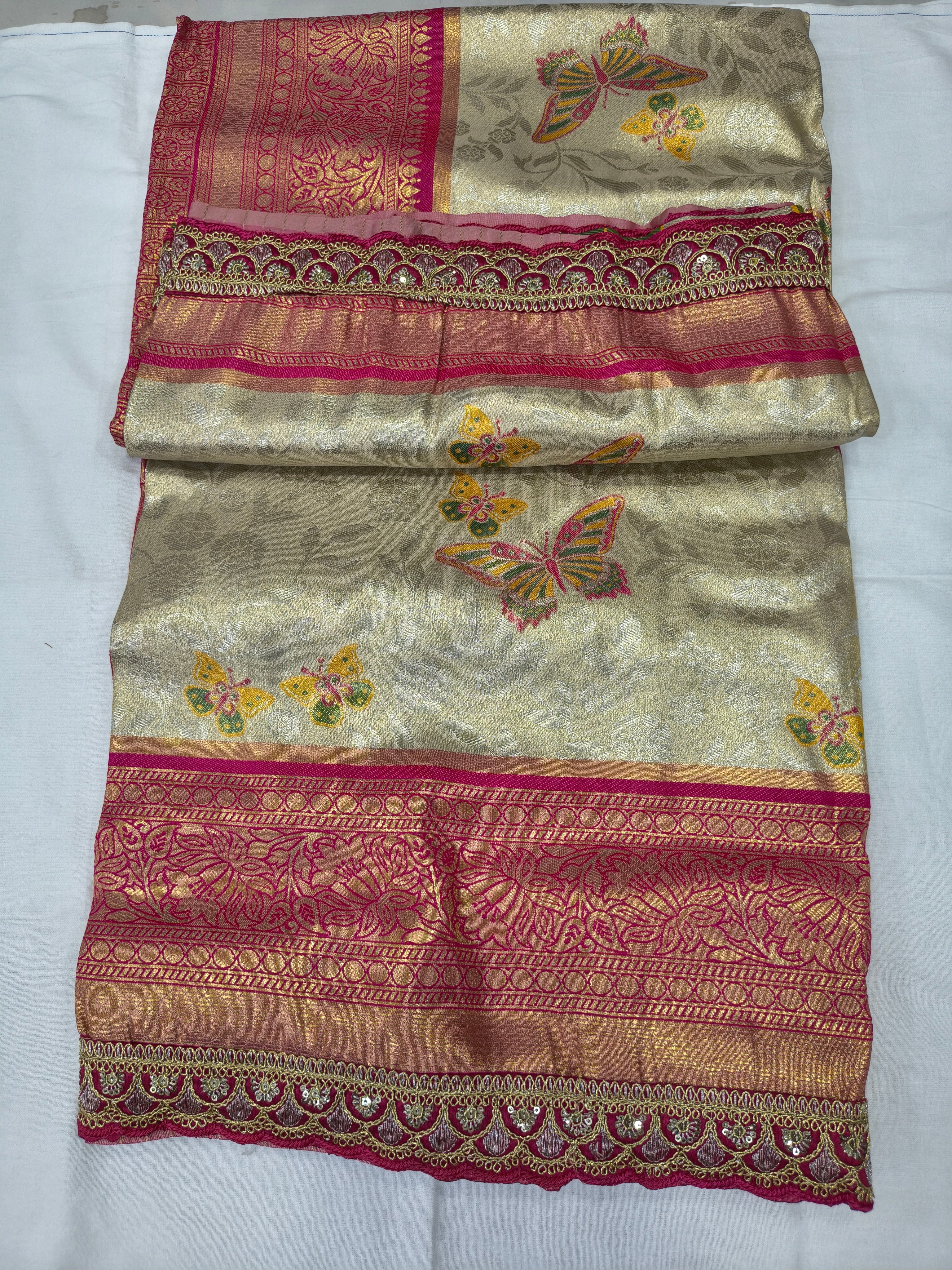Folded off-white Banarasi silk saree with red-pink border, floral and butterfly motifs