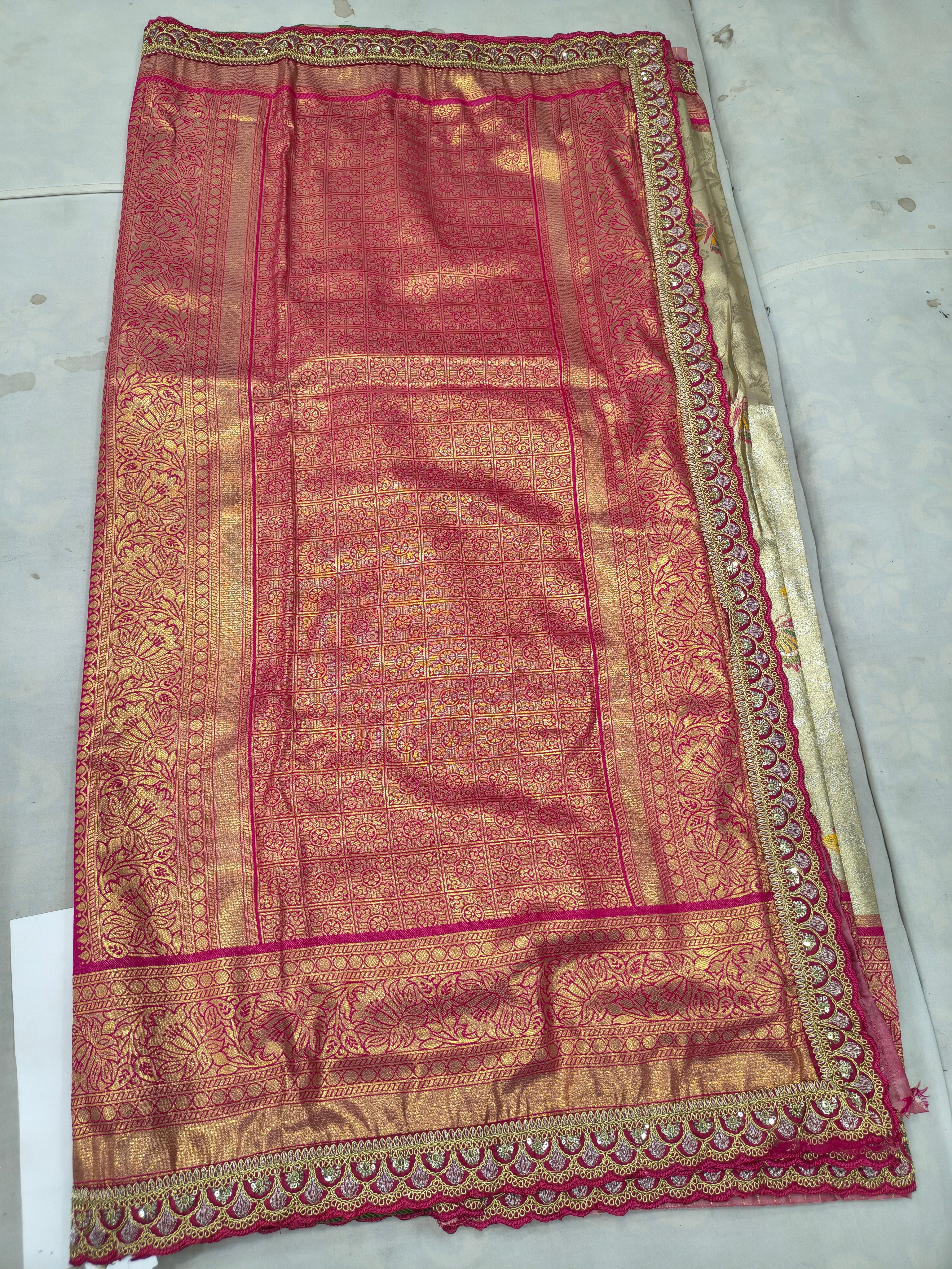 Pink Banarasi silk saree fabric with gold motifs and ornate hot-pink border, flat lay