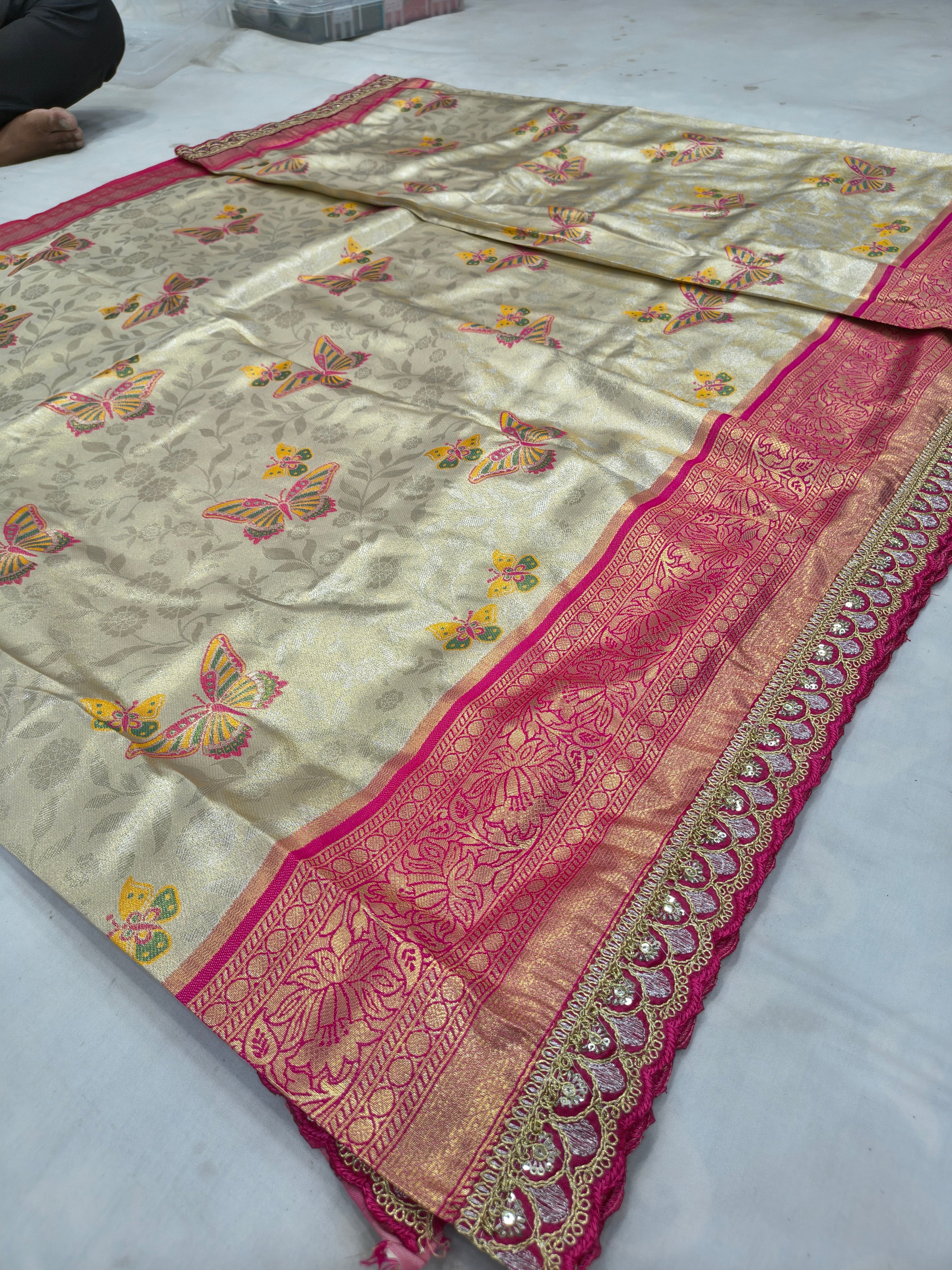 Off-white Banarasi silk saree with butterfly motifs and hot-pink border, laid flat