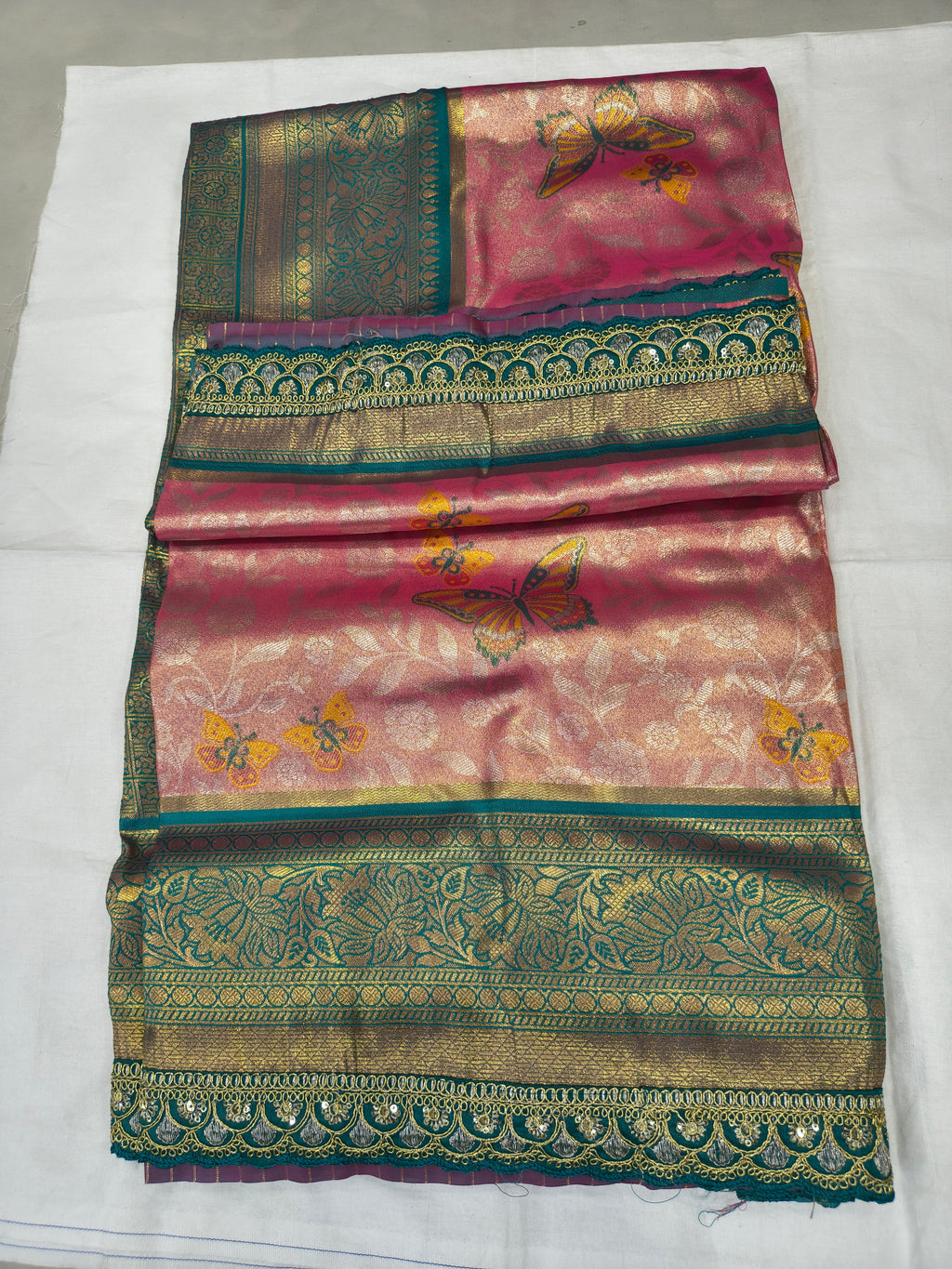 Folded pink and teal Banarasi silk saree with ornate gold border