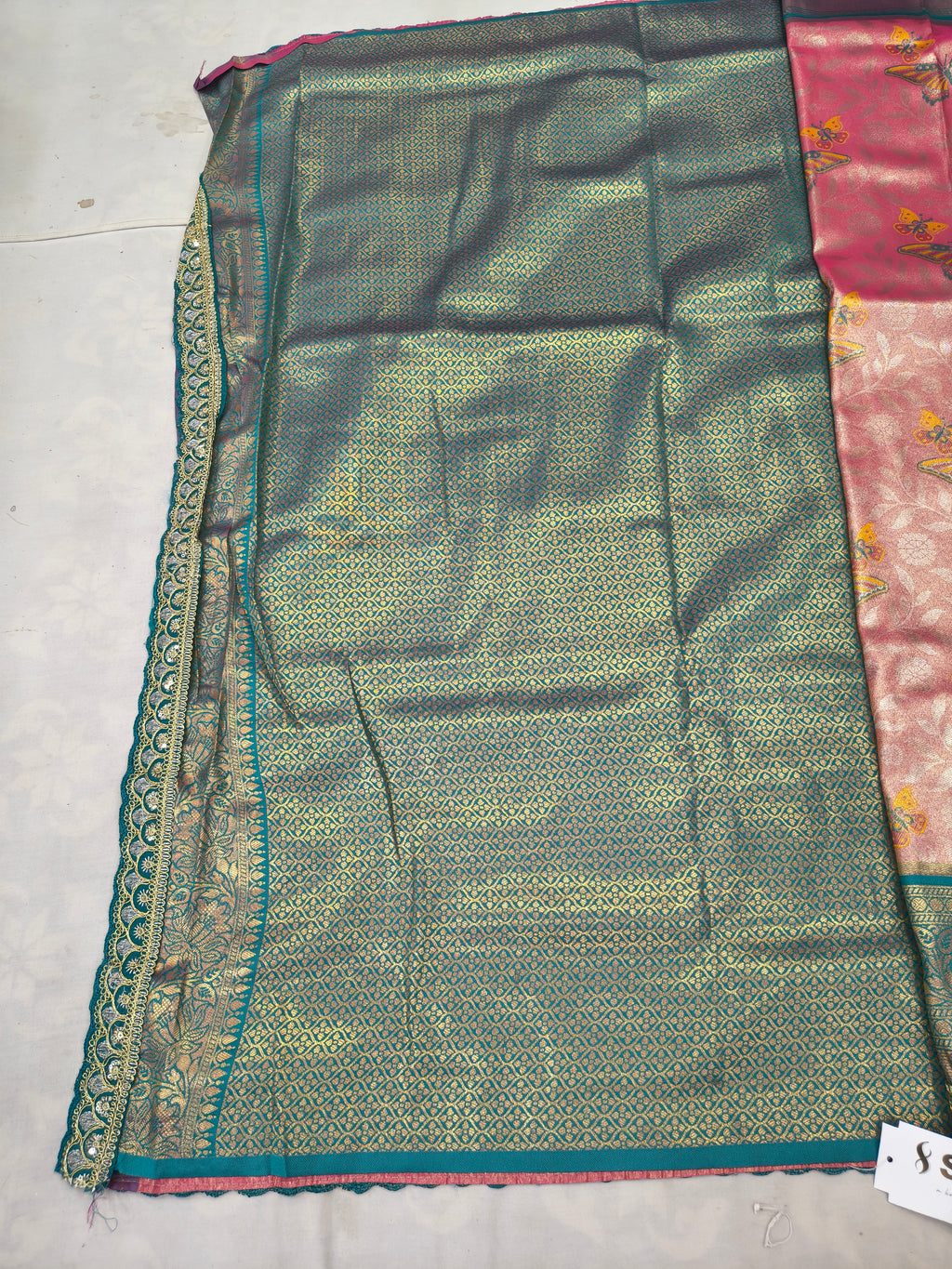 Teal Banarasi silk saree fabric with intricate gold-trim edge