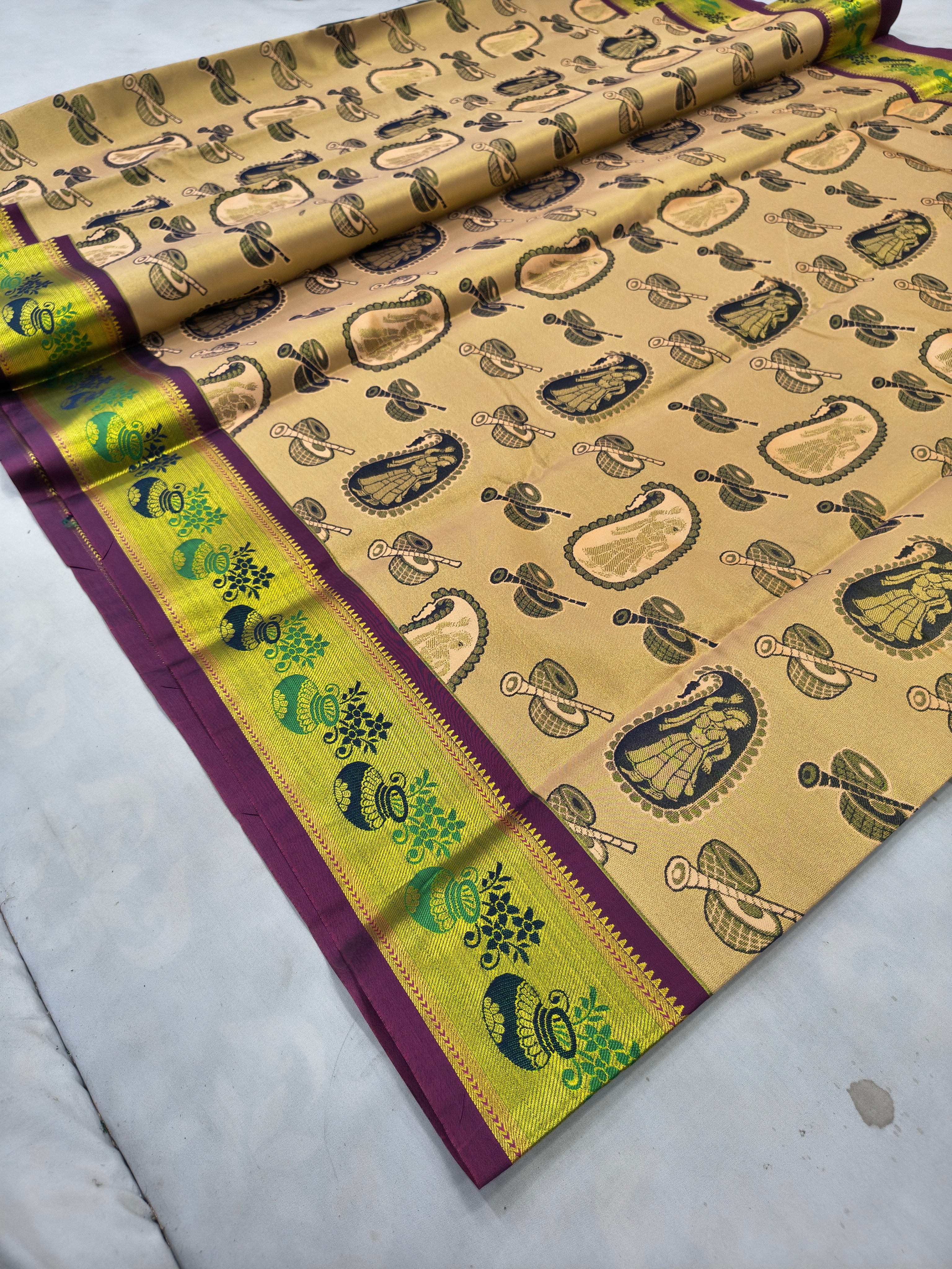 Beige silk saree laid flat with green border and patterned motifs, purple edge