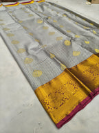 Close-up grey silk saree with gold heart motifs, mustard-gold border and red trim
