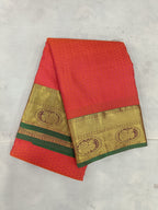 Red silk saree with gold border and green accent, folded with pallu visible