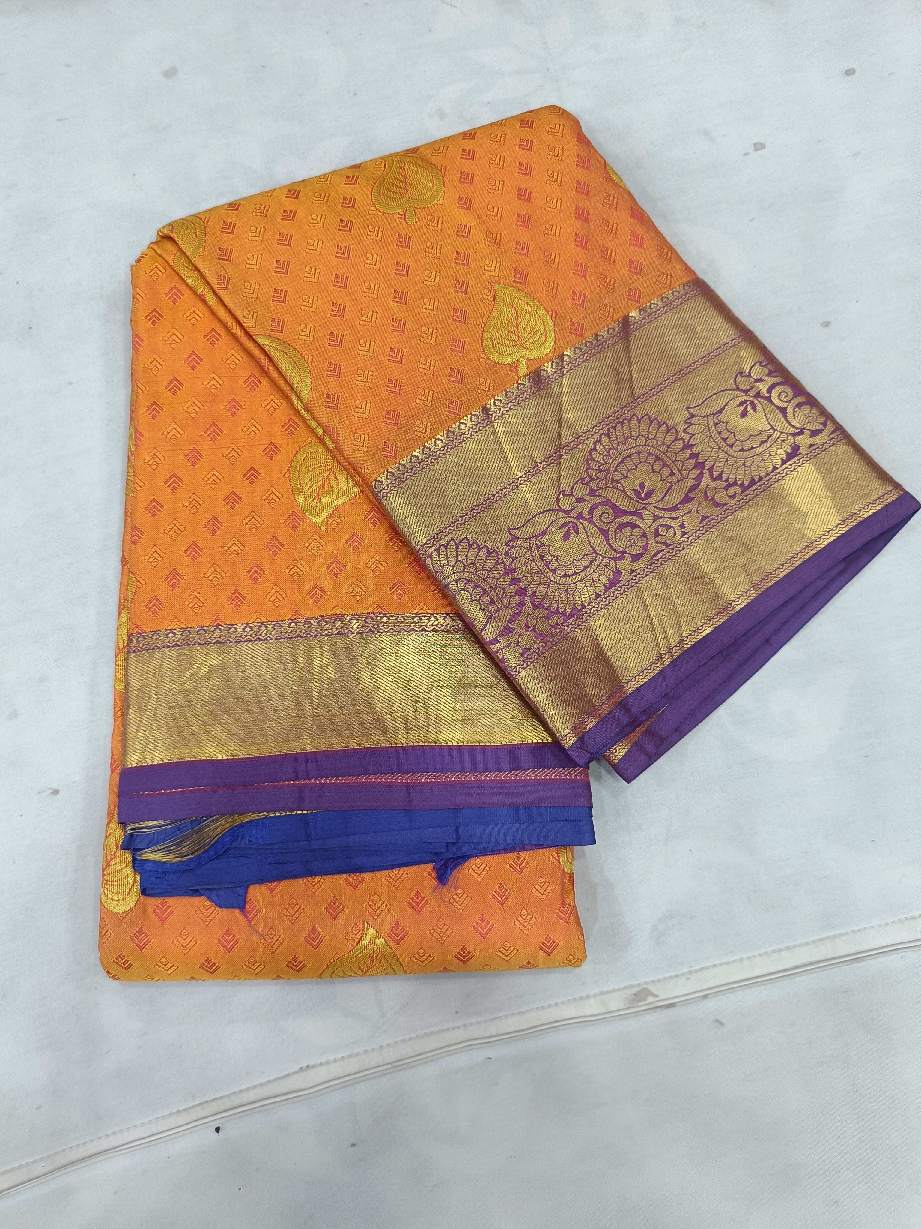 Folded mustard silk saree with blue border and gold woven pallu