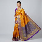 Women’s mustard silk saree with blue pallu, gold zari border, and patterned body